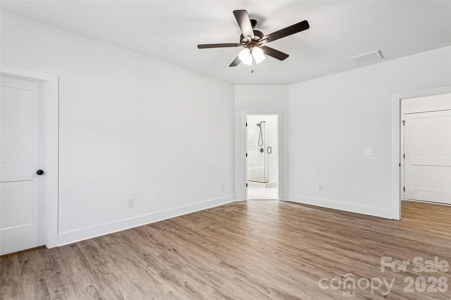 Guest bedroom with ceiling fan, en-suite bathroom doorway, and double closet doors