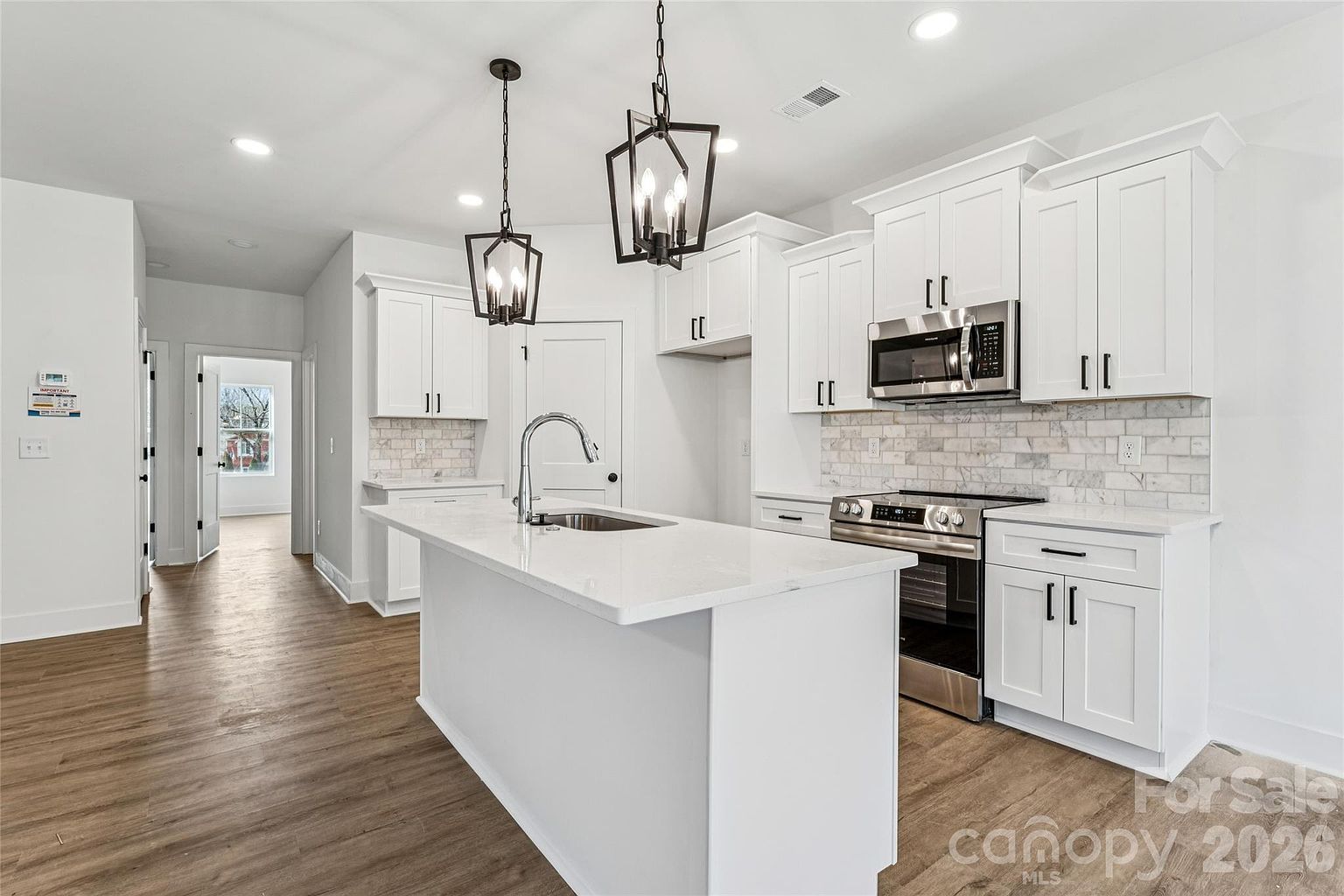 Kitchen with white shaker cabinets, quartz countertops, marble-tile backsplash, stainless steel appliances, and pendant lantern lights