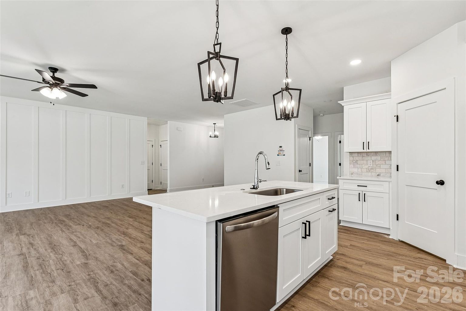 Kitchen island viewed from the living room showing the dishwasher, pendant lights, and pantry cabinetry