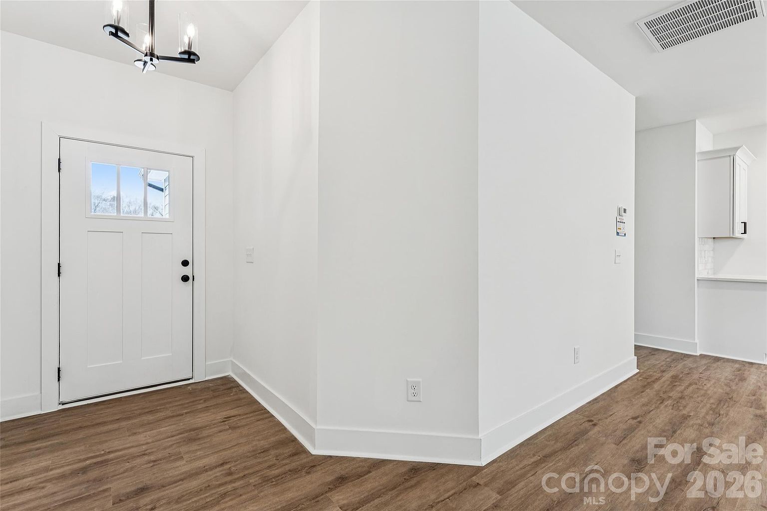 Entry foyer with craftsman front door, modern chandelier, and sightline through to the kitchen