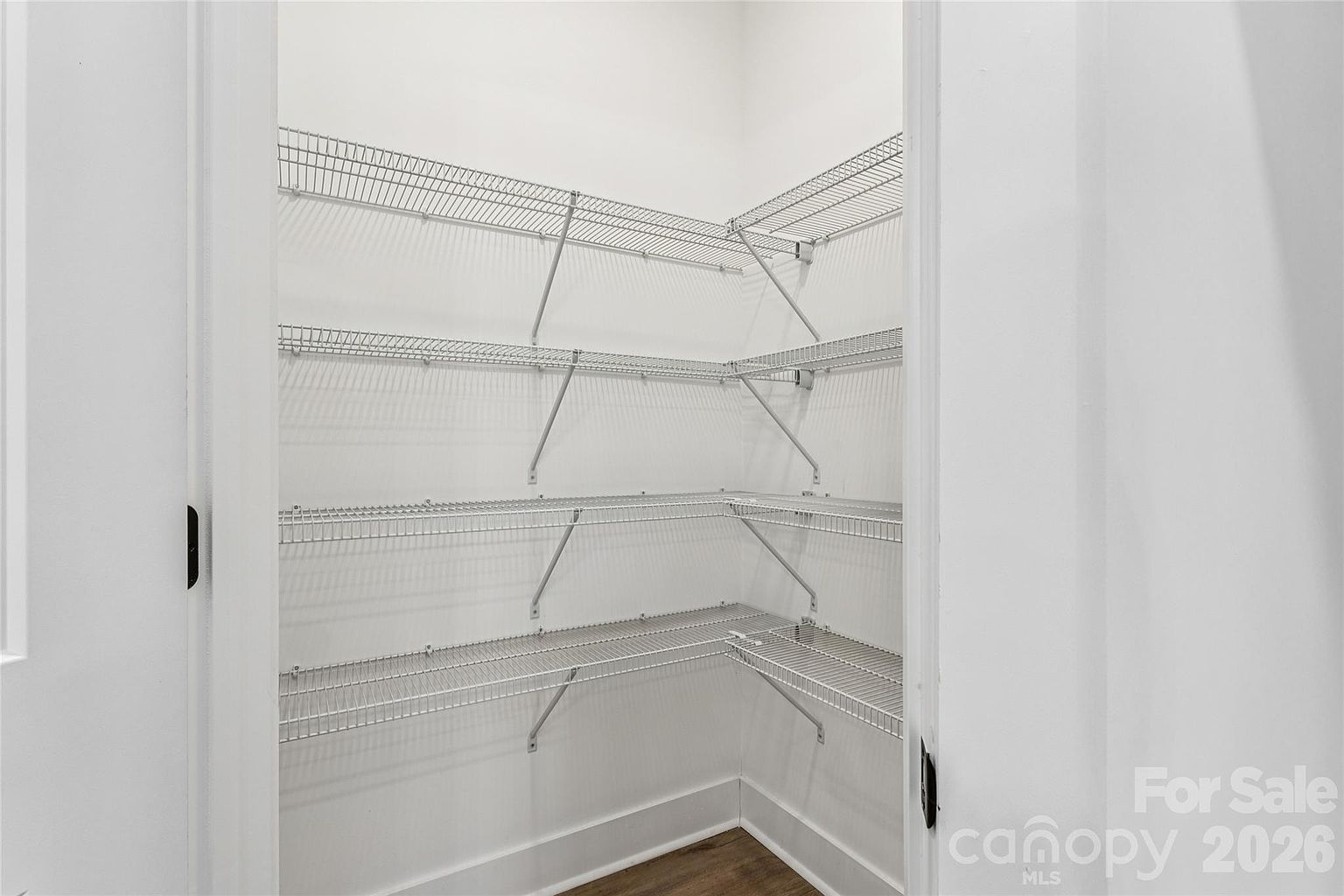 Walk-in pantry with multiple levels of wire shelving and hardwood-style flooring