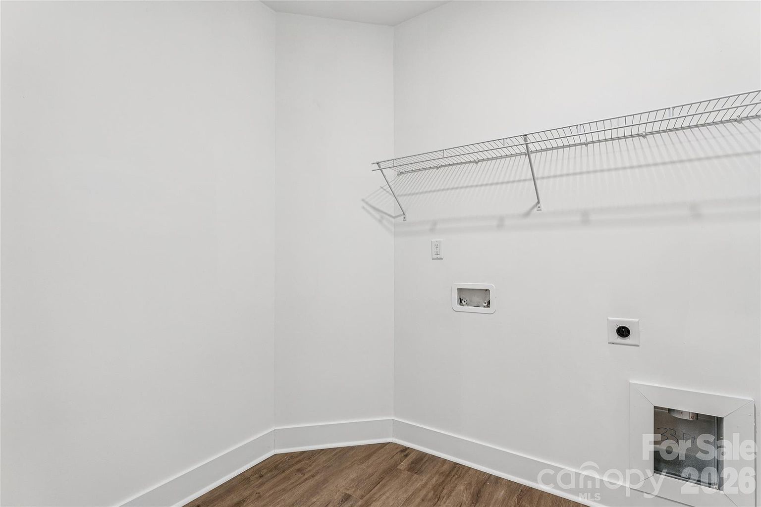 Laundry room with wire shelf, washer and dryer hookups, and hardwood-style flooring