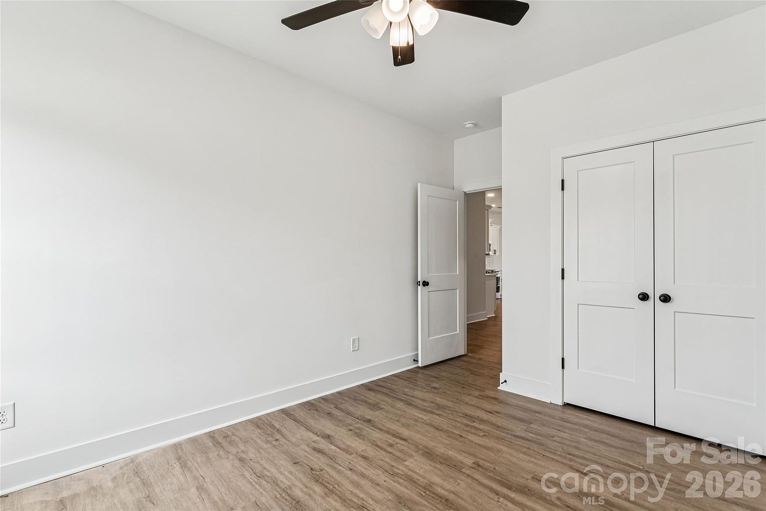 Bedroom with ceiling fan, double closet with panel doors, and doorway opening toward the main living area