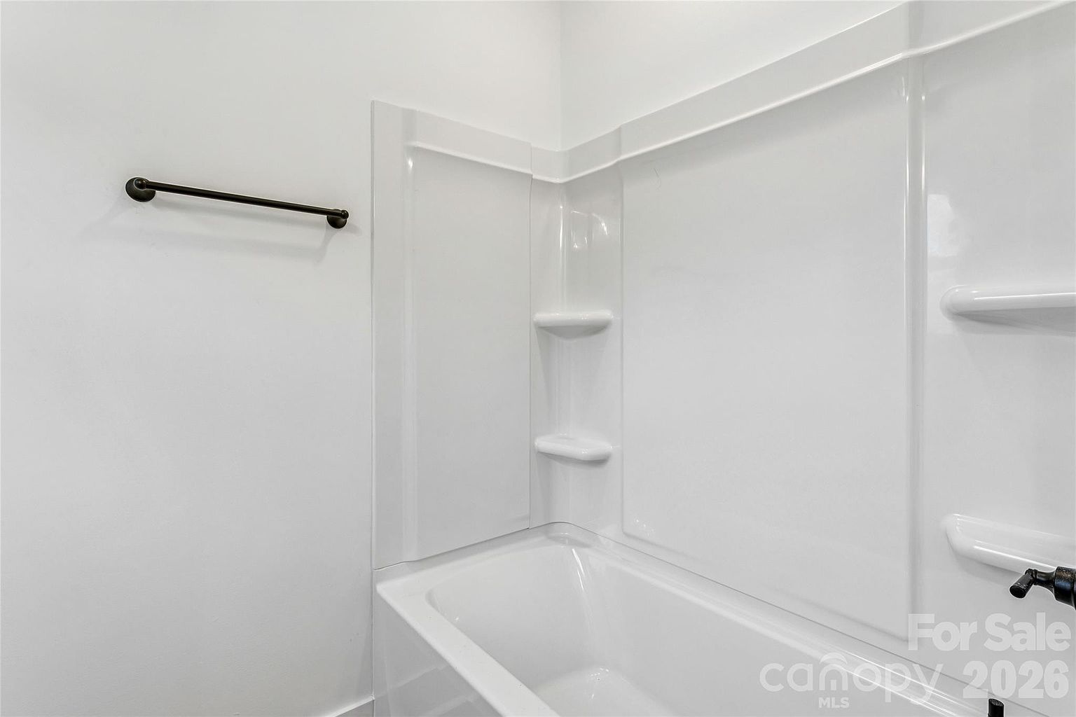 Bathtub and shower combination with grab bar, built-in corner shelves, and oil-rubbed bronze fixtures