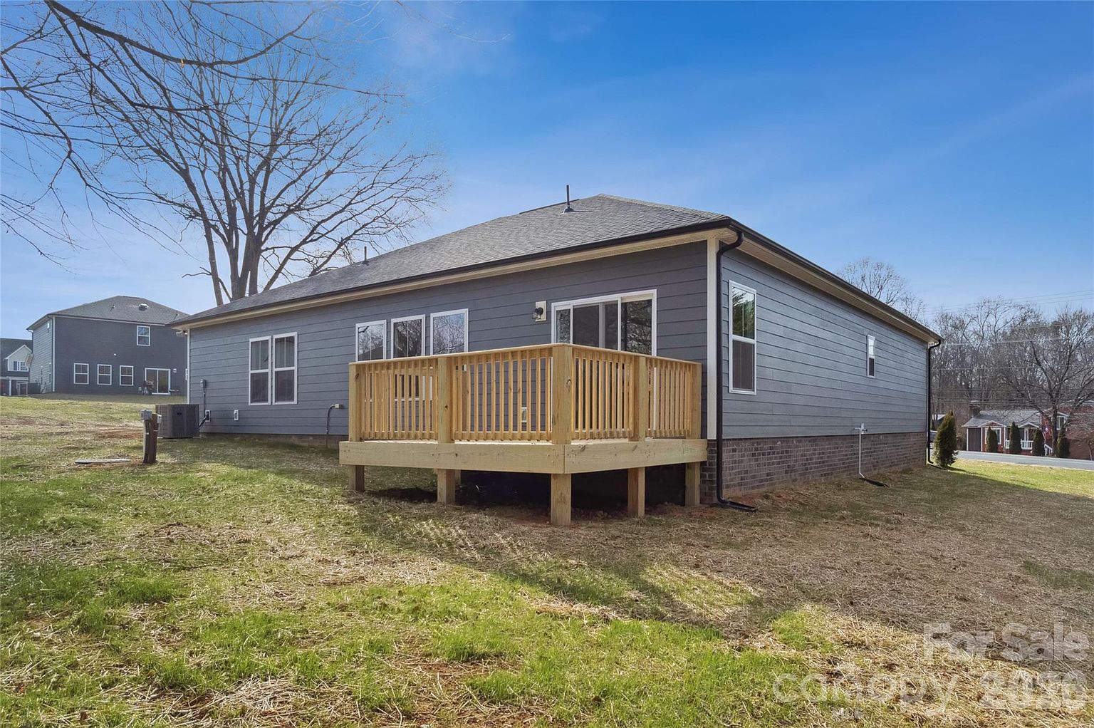 Rear exterior of the home showing the wooden deck, large windows, and a roomy fenced backyard